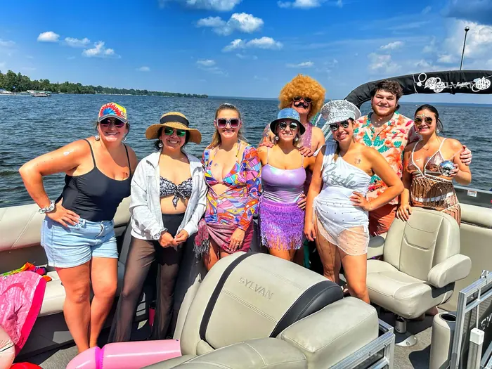 A disco-themed bachelorette party with the bride in a Bride hat aboard the Sylvan pontoon