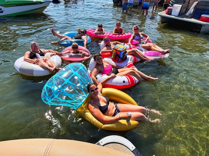 Guests relaxing on inflatable floats next to the pontoon at the sandbar