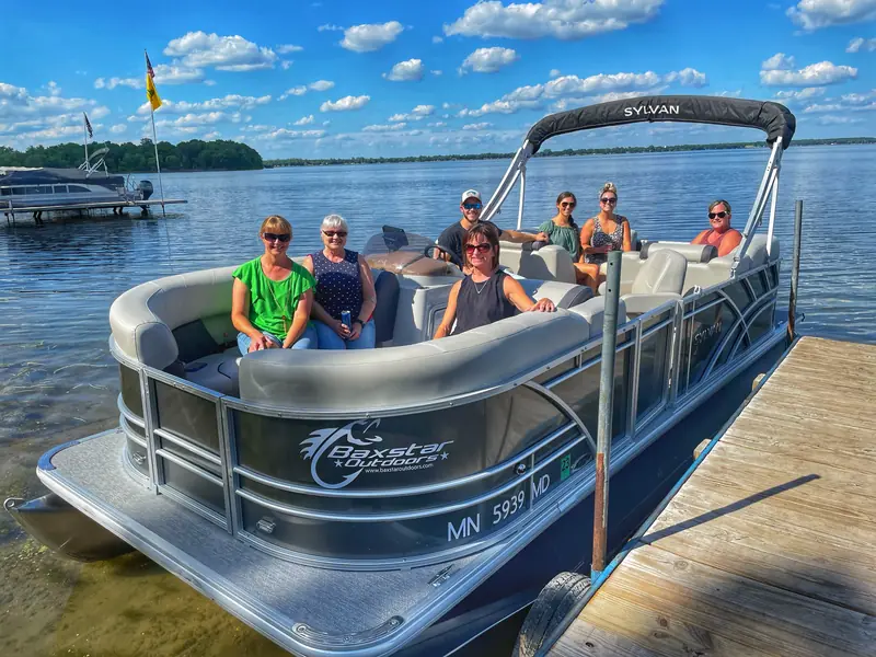 A group of guests seated aboard the Baxstar Outdoors Sylvan pontoon on a sunny day