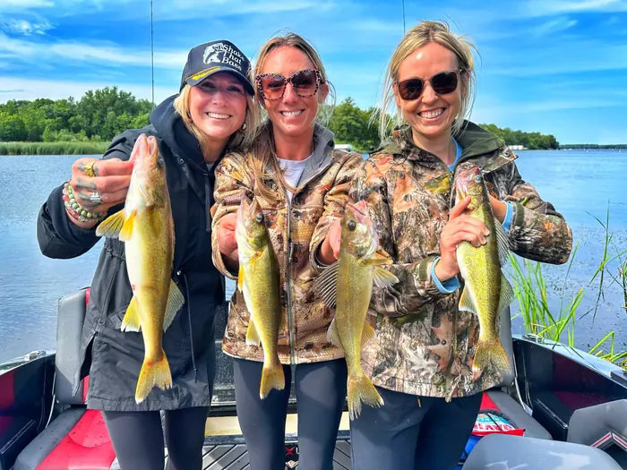 Three women holding walleyes aboard the Baxstar Fishing Vexus boat